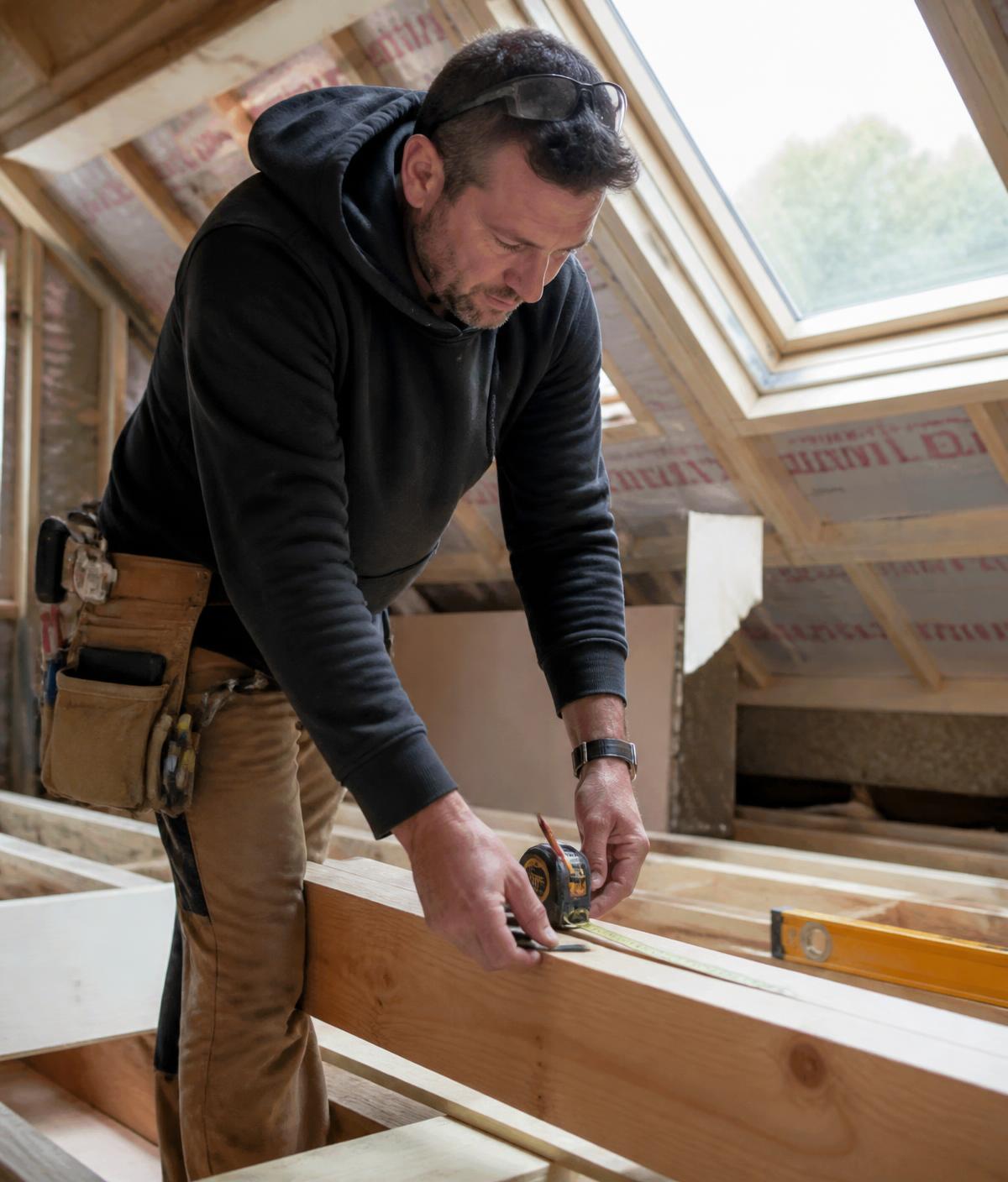 Carpenter measuring timber joists during a residential loft conversion